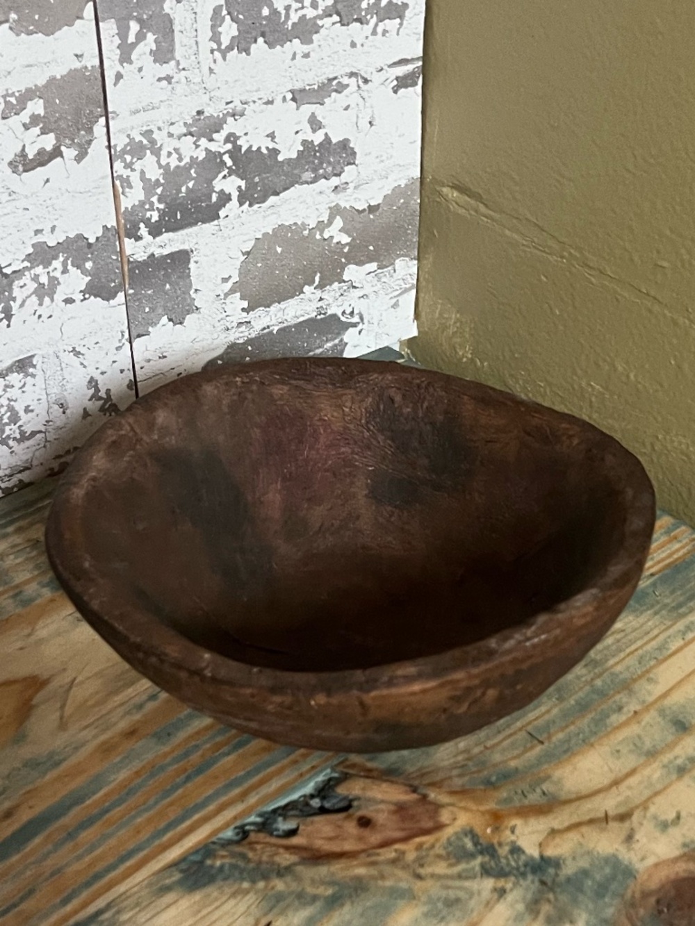 Small, hand-carved primitive wooden bowl featuring a dark, rustic patina